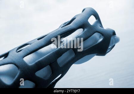 Handschienen-Korsett-Prothese auf 3D-Drucker aus geschmolzenem schwarzem Kunststoffpulver auf der Hand gedruckt. Kunststoffüberlagerung für Fixierer für medizinische Orthesen auf 3D-Drucker erstellt. Neue moderne medizinische 3D-Drucktechnologie, Stockfoto