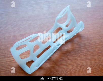 Handschienen-Korsett-Prothese auf 3D-Drucker aus geschmolzenem weißem Kunststoffpulver auf Tisch gedruckt. Kunststoffüberlagerung für Fixierer für medizinische Orthesen auf 3D-Drucker erstellt. Neue moderne medizinische 3D-Drucktechnologie Stockfoto