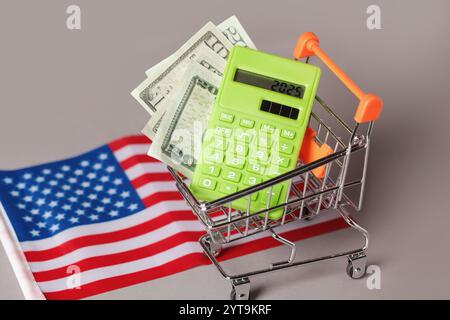 Einkaufswagen, grüner Rechner, amerikanische Flagge. Konzeptinflation für Lebensmittelkosten und Konsumverhalten. Lebenshaltungskosten Stockfoto