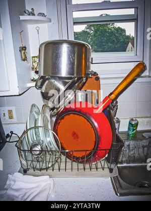 Gekonnt stapeltes Geschirr mit einer großen orangen belgischen Bratpfanne auf dem Trockenregal in einer Küche in Ludington, Michigan, USA. Stockfoto