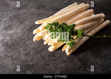 Frischer weißer Spargel auf schwarzem Hintergrund. Saisonales Frühlingsgemüse auf modernem schwarzem Schiefer. Sonnige Küchenszene für ein gesundes Gastronomie-Konzept mit Platz für Text. Stockfoto