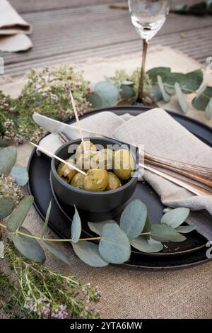 Mediterraner Tisch mit Oliven, im natürlichen Boho-Stil eingerichtet. Vertikaler Hintergrund für Hochzeitsfeiern und Urlaub Gastronomie. Stockfoto