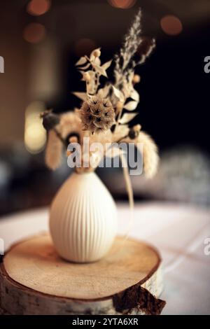 Wunderschönes getrocknetes Blumenbouquet im natürlichen Boho-Stil mit stimmungsvollem Bokeh. Nachhaltige Dekoration für Hochzeiten und Feiertage. Vertikales Blumenstillleben mit Fokus auf eine Blüte. Kurze Schärfentiefe. Stockfoto