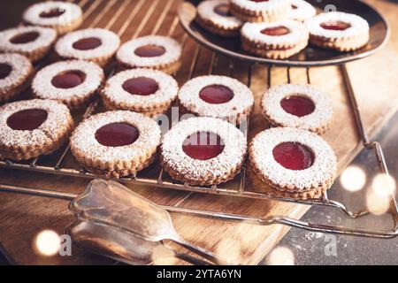 Traditionelle Linzer Plätzchen mit Johannisbeermarmelade frisch aus dem Ofen. Hausgemachte österreichische Kekse auf Holzbrett mit stimmungsvollem Bokeh. Stockfoto