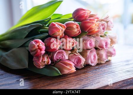 Blumenstrauß aus wunderschönen rosa Rosen und Tulpen auf dunklem Holz. Konzept Hintergrund für Muttertag, valentinstag und Hochzeiten. Stockfoto