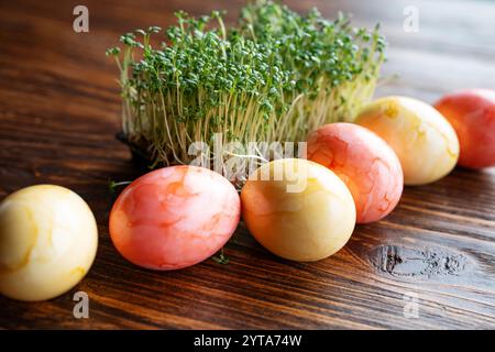 Farbenfrohe ostereier mit frischer Kresse auf rustikalem Holz. Nahaufnahme. Hintergrund für Frühling und ostern. Stockfoto