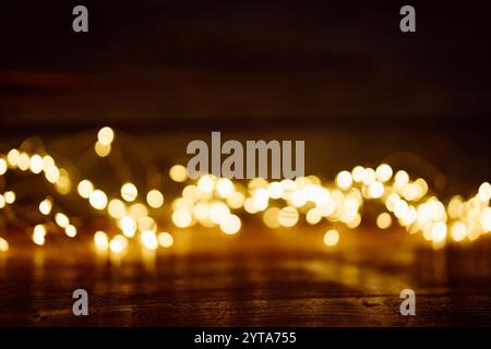 Verschwommene goldene Lichter auf dunklem Holz. Abstrakter weihnachtshintergrund mit leerem Holztisch. Für Produktdekorationen verwenden. Stockfoto