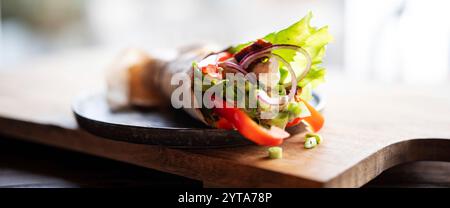 Tortilla-Wrap mit frischen Gemüse und gebratenem Hähnchenfleisch auf einem Teller. Hintergrundkonzept mit für gesunde Ernährung. Kurze Schärfentiefe. Stockfoto