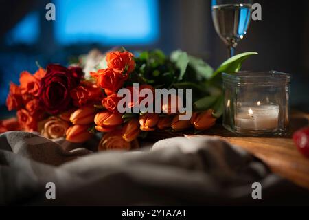 Romantisches Stillleben mit roten Rosen und Tulpen, Champagner und Kerzenlicht. Hintergrundkonzepte für Hochzeit und valentinstag. Stockfoto