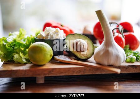 Gesundes Gemüse und Zutaten auf hölzernem Schneidebrett vor dem hellen Küchenfenster. Hintergrundkonzept für eine gesunde Ernährung. Leerzeichen für Text. Stockfoto