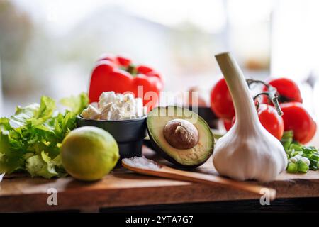 Gesundes Gemüse und frische Zutaten auf hölzernem Schneidebrett vor dem hellen Küchenfenster. Gesundes Nährstoffkonzept für eine Frühlingsdiät. Leerzeichen für Text. Stockfoto