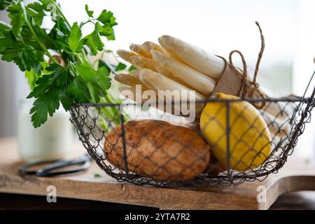 Frischer weißer Spargel und Kartoffeln. Frühlingsgemüse in einem Korb auf hölzernem Schneidebrett. Zutaten für ein gesundes Menü. Küche für die saisonale Gastronomie. Nahaufnahme. Stockfoto
