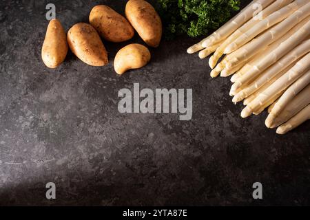 Saisonal weißer Spargel und frische Zutaten auf schwarzem Schiefer. Hintergrund für gesundes Nährstoffkonzept mit Textraum. Stockfoto