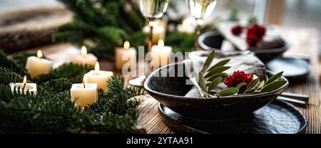 Festliche Tischdekoration zu weihnachten und Neujahr mit Sektgläsern und Kerzenlichtern auf Holztisch mit Tannenzweigen. Horizontaler Hintergrund für Lifestyle und Einladung. Stockfoto