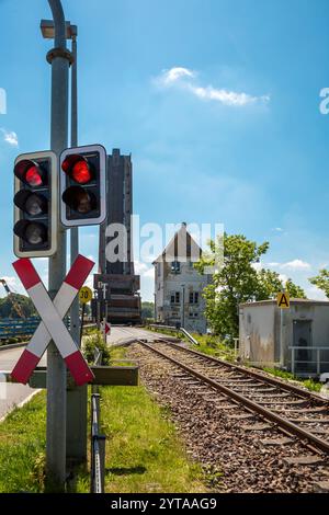 Rote Ampelanlage mit Andreaskreuz und Bahngleisen an einer Haltestelle Stockfoto