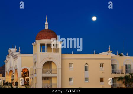 Ein großes Gebäude mit einer Kuppel oben und einem Mond am Himmel. Das Gebäude ist weiß und hat ein rotes Dach Stockfoto