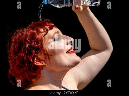 Frau kühlt sich ab, indem sie Wasser auf den Kopf gießt. Stockfoto