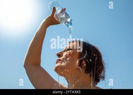 Frau kühlt sich ab, indem sie Wasser auf den Kopf gießt. Stockfoto