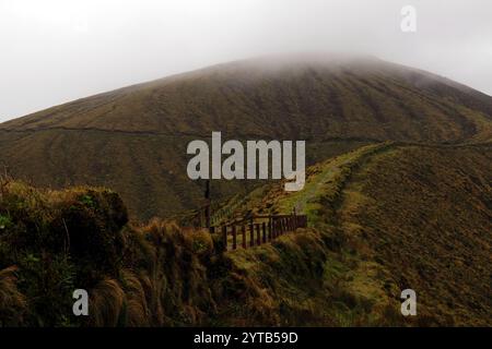 Ein landschaftlich reizvoller Pfad führt entlang des Gipfels des nebeligen Caldeira auf den Azoren und lädt Abenteurer ein, üppige Landschaften und atemberaubende Panoramablicke zu erkunden Stockfoto