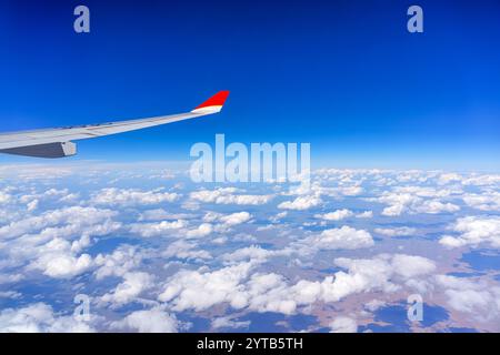 Flügel eines Flugzeugs, das über flachen Kumuluswolken über Plateaus fliegt. Stockfoto