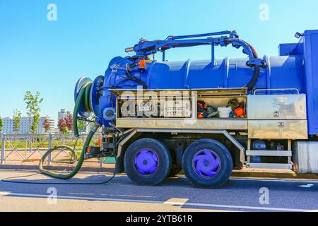 Pumpen von Wasser aus Abwasserkanälen während des Straßenbaus in der Stadt. Fahrzeug mit blauem Wassertank. Stockfoto