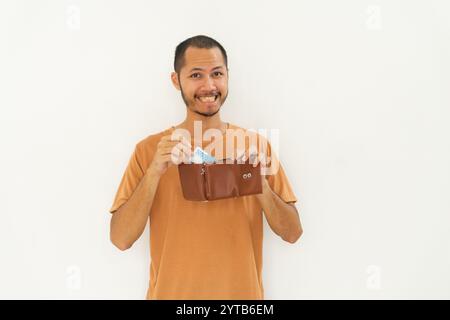 Junge Männer, die ein orangefarbenes Hemd tragen, zeigen Brieftasche und Geld isolierten weißen Hintergrund Stockfoto