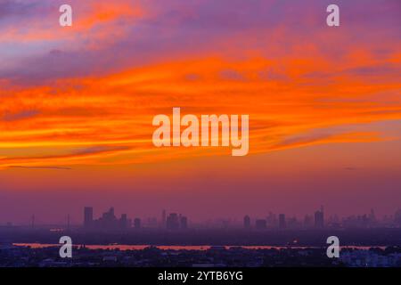Abendlicher Blick auf die Silhouetten der Stadt von Gebäuden und Wolkenkratzern, den sterbenden Himmel nach Sonnenuntergang und atemberaubende rote Wolken. Stockfoto