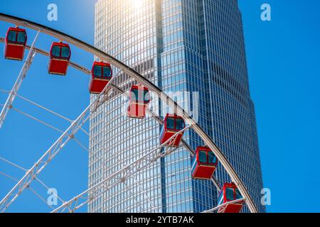 Riesenrad gegen Glashochhaus mit blauem Himmel Stockfoto