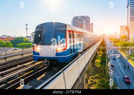 Elektrische Zugbewegung Unschärfeeffekt Eisenbahnwaggons rasen die Fahrten entlang der Route im Sonnenuntergang Sky Railway Road Viadukt zwischen der modernen Stadt des Bauens Stockfoto