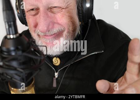 Ein siebzigjähriger Podcaster, der Gesten und Lächeln macht Stockfoto