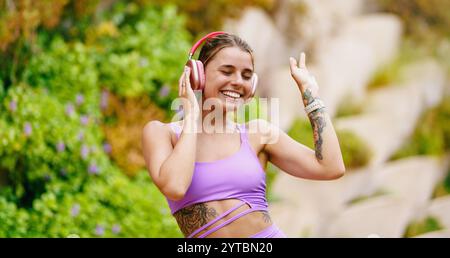 Fröhliche junge Frau, die fröhlich Musik genießt, während sie Zeit im Freien in der Sonne verbringt Stockfoto
