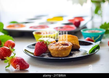 Süße Quark-Muffins mit Erdbeerfüllung, auf einem Teller auf einem Holztisch. Stockfoto