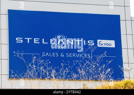 Großes blaues Stellantis-Schild mit Firmenlogo und Slogan für Vertrieb und Dienstleistungen, montiert an einem modernen Gebäude Stockfoto