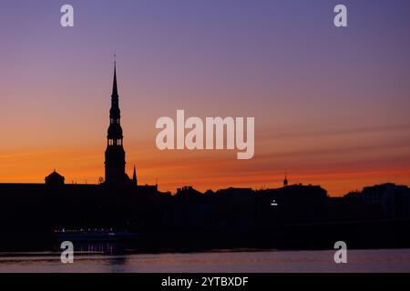 Eine wunderschöne Rigaer Stadtlandschaft während des farbenfrohen Sonnenaufgangs. Gebäude vor buntem Himmel. Nordeuropäischer Morgen mit warmem Himmel. Stockfoto