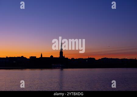 Eine wunderschöne Rigaer Stadtlandschaft während des farbenfrohen Sonnenaufgangs. Gebäude vor buntem Himmel. Nordeuropäischer Morgen mit warmem Himmel. Stockfoto