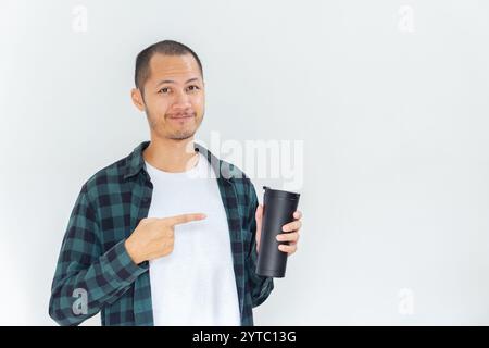 Junge asiatische Männer, die Flanell und Hemd tragen, zeigen schwarzen Tumbler mit einem Lächeln auf isoliertem weißen Hintergrund Stockfoto