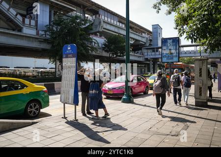 Bangkok, Thailand. Dezember 2024. Eine Einheimische wird gesehen, wie sie einer Frau hilft, vor dem Schild für Buslinien, an einer Bushaltestelle, nahe dem Eingang zum Chatuchak Park in Bangkok. Der Chatuchak Park ist ein öffentlicher Park in Bangkok, der einen friedlichen Rückzugsort mit Grünflächen, einem See und Erholungsgebieten abseits der Hektik der Stadt bietet. (Foto: Nathalie Jamois/SOPA Images/SIPA USA) Credit: SIPA USA/Alamy Live News Stockfoto
