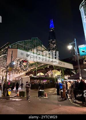 Borough Market London bei Nacht mit Weihnachtskranz und Lichtern. Die Scherbe leuchtet blau im Hintergrund mit Menschen. Stockfoto