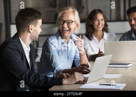 Reife und junge Mitarbeiter führen im Büro angenehme Gespräche Stockfoto