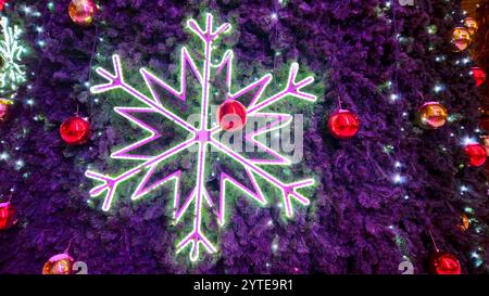 Große glühende Schneeflocke und rote Glaskugeln aus nächster Nähe auf dem Weihnachtsbaum, helle und schöne Neujahrs- und Weihnachtsdekorationen, Feiertagshintergrund Stockfoto