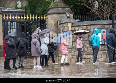 Windsor, Berkshire, Großbritannien. Dezember 2024. Die Leute stehen an, um in Windsor Castle in Windsor, Berkshire, mit ihren Sonnenschirmen zu gehen. Eine Wetterwarnung für Wind in MET Office Yellow bleibt bis 06,00 Uhr morgen früh, Sonntag, den 8. Dezember, in Kraft. Quelle: Maureen McLean/Alamy Live News Stockfoto