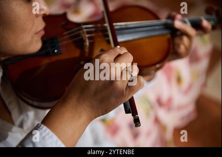 Ein detaillierter Blick auf die Hände eines Musikers, der fachmännisch eine Geige spielt und die Kunstfertigkeit und Präzision der Streichinstrumente zeigt. Stockfoto