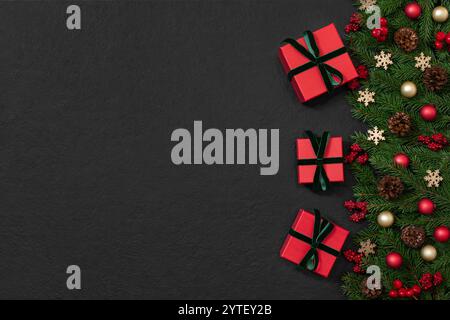 Weihnachtsrand mit Geschenken, Tannenzweigen und festlicher Einrichtung auf schwarzem Hintergrund. Neujahrshintergrund mit Kopierbereich. Draufsicht, flach. Stockfoto