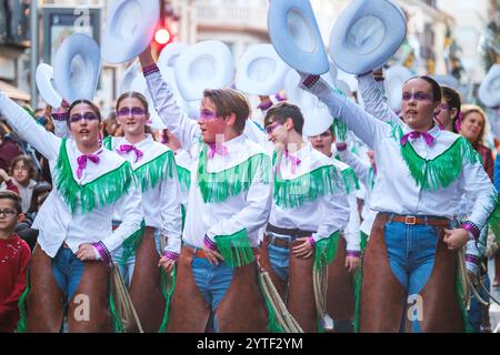 Das Bild zeigt eine Gruppe von Personen, die an einer Parade oder einem Festival teilnehmen. Sie tragen passende Kostüme in weiß Stockfoto