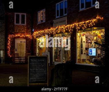 Holt, Norfolk, Großbritannien – 06. Dezember 2024. Das Äußere eines Buchladens, beleuchtet von Weihnachtslichtern an einem Dezemberabend. Gefangen im Norden Norfolk Stockfoto