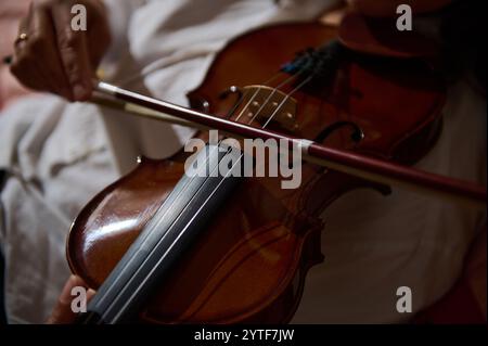 Ein intimer, detaillierter Blick auf einen Musiker, der im Inneren eine Geige spielt, der Handwerkskunst hervorhebt. Stockfoto