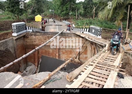 Sukabumi, Indonesien. Dezember 2024. Ein Motorradfahrer überquert eine provisorische Holzbrücke in der Nähe einer durch Überschwemmungen beschädigten Brücke im Dorf Cisarakan in Sukabumi Regency, West Java Province, Indonesien, 7. Dezember 2024. Fünf Leichen wurden geborgen und sieben weitere werden vermisst, nachdem Sturzfluten und Erdrutsche Hunderte von Häusern und Infrastruktur in Indonesiens West-Java-Provinz zerstört haben, sagte ein Beamter am Freitag. Quelle: Rangga Firmansyah/Xinhua/Alamy Live News Stockfoto