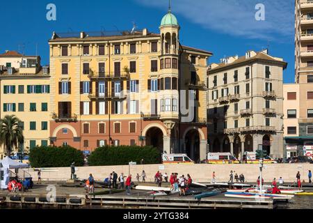 Savona. Italia - 07. Dezember 2024: Die malerische Uferpromenade von Savona, Italien, mit wunderschöner historischer Architektur, voller Menschen und Stockfoto