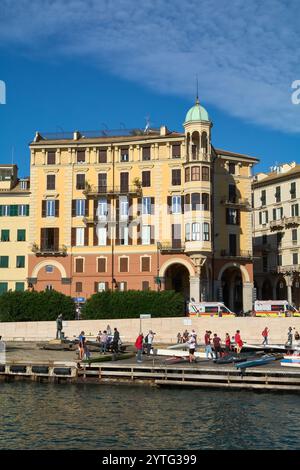 Savona. Italia - 07. Dezember 2024: Eine lebendige Küstenszene in Savona, Italien, mit historischen Gebäuden mit farbenfrohen Fassaden und vielen Menschen Stockfoto