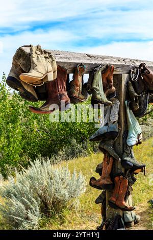 Ein Haufen Cowboystiefel hängen an einem Pfosten. Die Stiefel sind in verschiedenen Farben und Stilen und hängen alle kopfüber. Die Szene hört auf Stockfoto